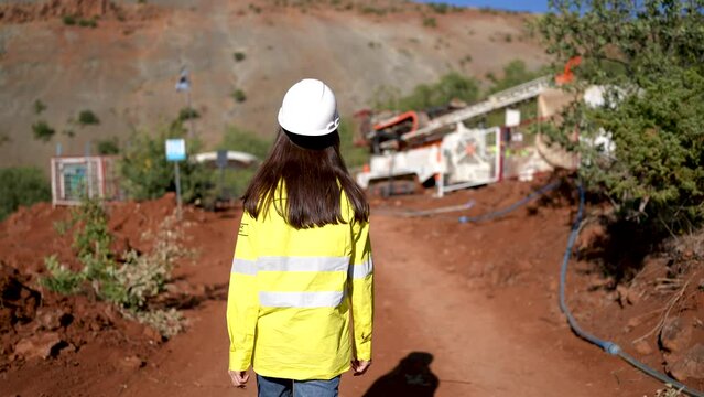 Female Engineer Working in Gold Mine walking on red soil