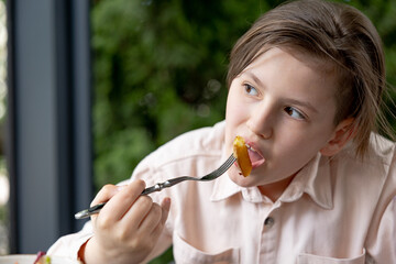 Teen boy has fried fries potatoes in outdoor cafe