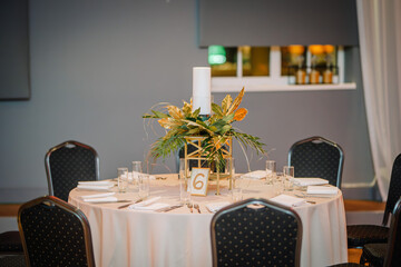 A round table at the event is decorated with gold and green leaves