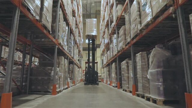 A forklift is driving through a large warehouse. Moving through a modern warehouse. Large modern warehouse in the factory