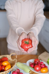 Age woman holding a large ripe tomato in her hands