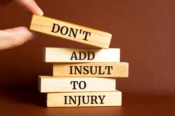 Wooden blocks with words 'Don't add insult to injury'.