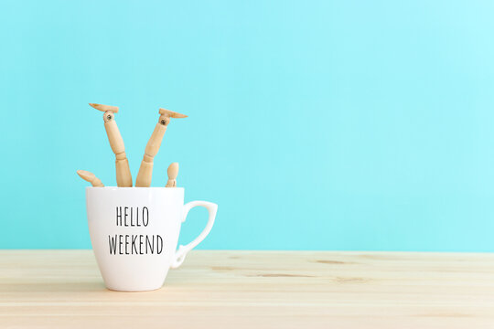 Wooden figure jumping from coffee mug with the text hello weekend