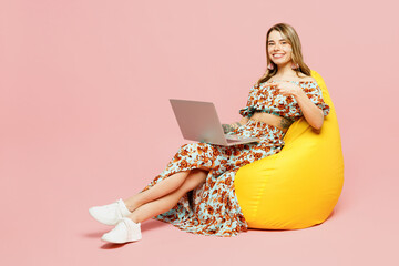 Full body young IT woman wear summer casual clothes sit in bag chair hold use work point finger on...