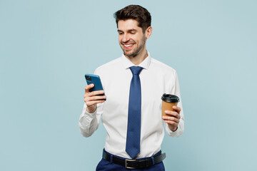Young cheerful employee business man corporate lawyer wear classic formal shirt tie work in office hold use area mobile cell phone drink coffee isolated on plain light blue background studio portrait.