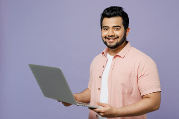 Young IT Indian man he wear pink shirt white t-shirt casual clothes hold use work on laptop pc...