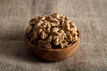 Bowl full of peeled walnuts on burlap sack