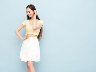 Image portrait of optimistic woman in yellow  t-shirt and white skirt. Carefree stylish model with long hair. Smiling female posing in studio. Isolated. Looks delightful and cute. Slim