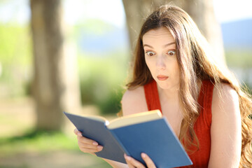 Obraz premium Perplexed reader reading a paper book outdoors