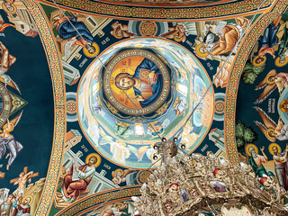 Fototapeta na wymiar Looking up to the detailed underside of the dome in an orthodox church with beautiful iconographic paintings and the light coming from above in Titan the southeast district in Bucharest, Romania.