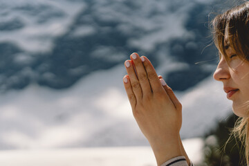Woman closed her eyes, praying near the mountain. Hands folded in prayer concept for faith, spirituality and religion. Peace, hope, dreams concept
