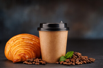 Aromatic coffee in a paper cup paired with a flaky croissant