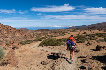 Young woman hiker with backpack trekking near Pico del Teide mountain in El Teide National park. Tenerife, Canary Islands, Spain