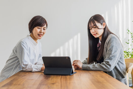 タブレットを見る日本人女性と女子学生