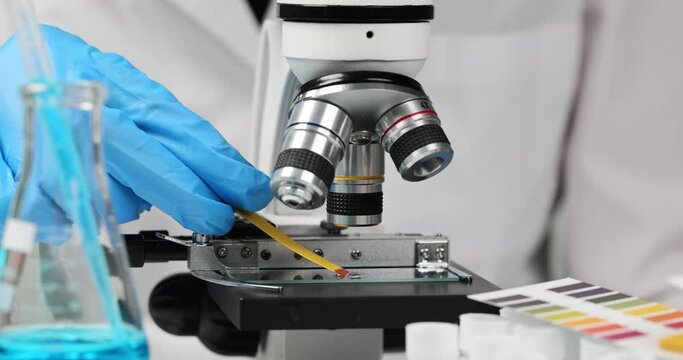 Scientist chemist holds in hands ph liquid test with microscope closeup. Chemical analysis and composition of water