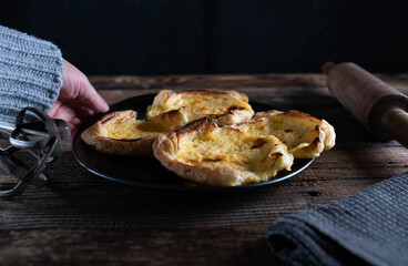 Homemade puff pastry tartlet with sour cream filling on wooden table
