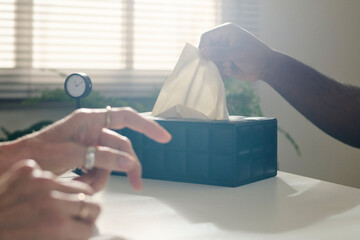 Hand of patient pulling paper napkin from box at desk in office