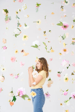 Smiling girl standing amidst falling flowers