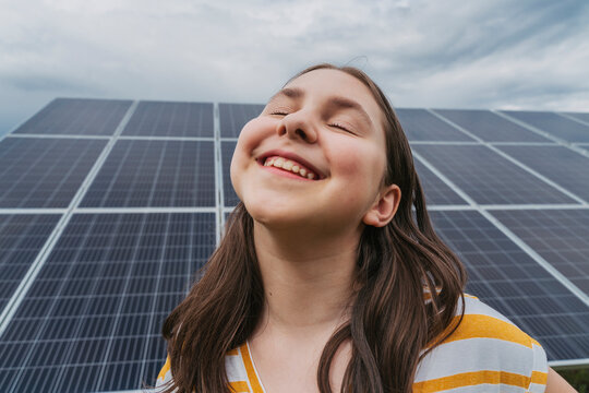 Happy girl with eyes closed in front of solar panels