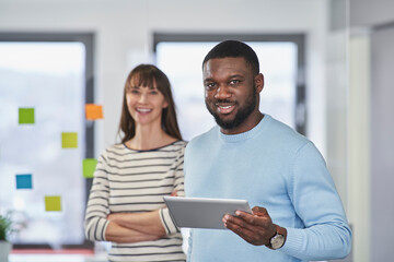 Smiling businessman holding tablet PC with coworker at office