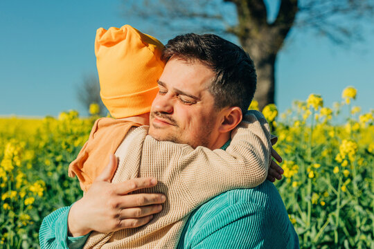 Father and son hugging at rapeseed field