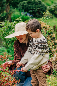 Smiling woman and son wearing sweaters in garden