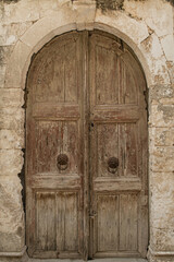 Fototapeta na wymiar Old ancient colourful textured door in a stone wall in Greece, Crete. Vintage doorway. Traditional European, Greek architecture. Summer travel