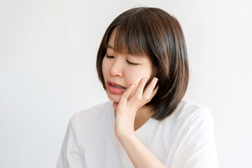 A woman touches her cheek showing pain due to a toothache.