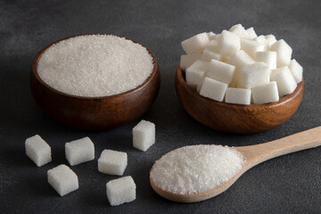 Fototapeta na wymiar Cube sugar and granulated sugar on black background 