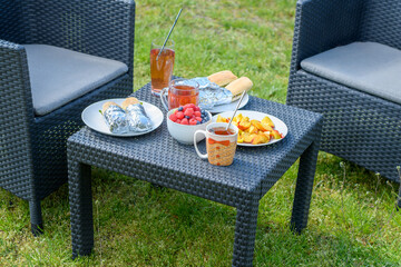 Śniadanie w ogrodzie na ratanowych meblach - obrazy, fototapety, plakaty