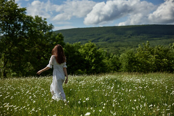 a free woman in a light dress runs through a field of daisies with her back to the camera