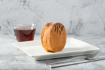 Chocolate New York roll or round croissant with tea on stone table