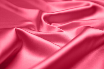Viva Magenta toned red magenta fabric atlas. Close up pink silk satin texture for sewing. Abstract background wallpaper. Twisted folds cloth. Trendy color of the year 2023. Fashion color pattern
