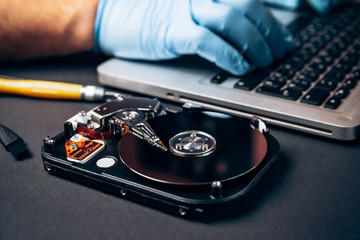 Obraz premium Computer service engineer technician workplace repairing fixing disassembled HDD hard drive data disc SSD, backup part of PC or laptop. Recovery, maintenance work, access file. Profession repairman