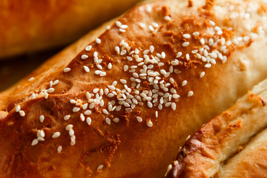 Close up shot homemade food baking concept. Fresh hot soft fluffy ginger golden brown sesame seeds buns pie bread dessert pastry in loaf pan. Bakery products, image with copy space.
