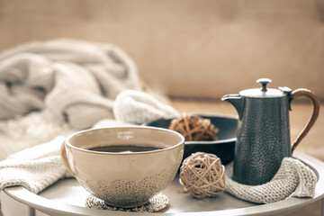 Home composition with a cup of tea and a teapot on a blurred background.