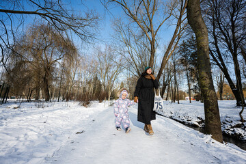 Mother and child walking on a sunny frosty winter day in the park.