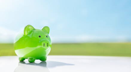 Green piggy bank against blue sky background savings, accounting, banking and business account or sustainable and environmentally friendly finance