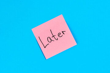 Pink sticker with the inscription Later on a blue background, top view.