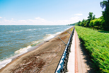 Boardwalk on the beach. Park is separated from the water by a fence. Beautiful summer landscape.