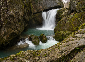 Naklejka na ściany i meble Waterfall with mossy rocks in mountain canyon, Svrakava waterfall near Banja Luka