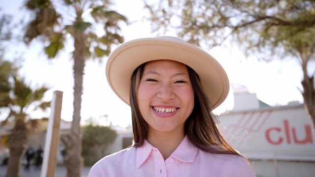 Portrait of a happy asian woman looking at camera smiling, standing outdoors on the sand beach. Summer holidays.