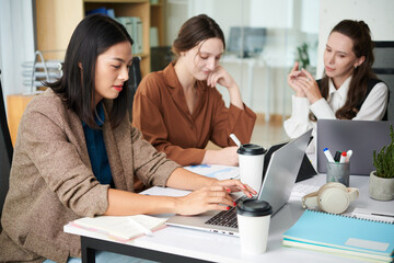 Team of businesswomen working on big project at office table