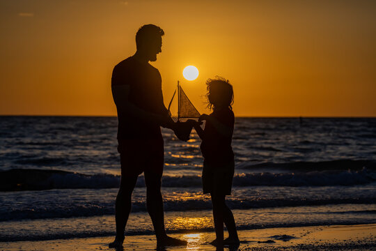 Father son little child having a happy moment together play with toy ship on summer beach. Parenting, fatherhood and fathers day concept. Friendly family dream on summer vacation.