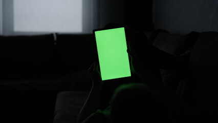 Naklejka premium Man at home lying on a couch with tablet pc with green screen