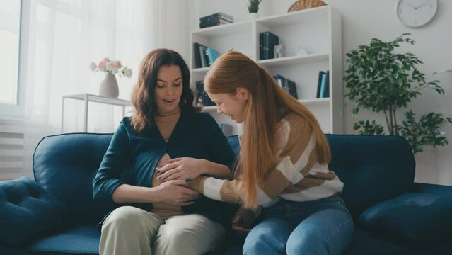 Teen girl feeling baby's moves and kicks in her mother's belly, happy family