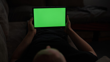 Naklejka premium Man at home lying on a couch with tablet pc with green screen