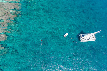Aerial view of beautiful sailing yacht in tropical turquoise ocean sea waters. Vibrant bright sunny...