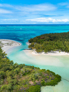 Beautiful island beach with palm trees and blue sky leading out to the open ocean. Ile Aux Cerfs, Mauritius. Aerial view of sandy beach. Aerial drone view of the beautiful tropical ocean beach.