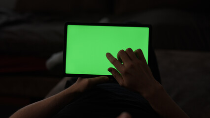 Naklejka premium Man at home lying on a couch with tablet pc with green screen